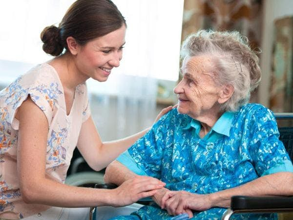 Aid talking with older woman with her hand on shoulder and arm