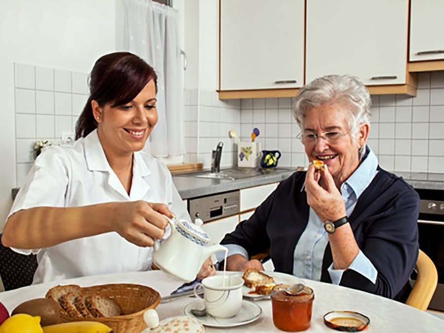 Aid helping patient with breakfast