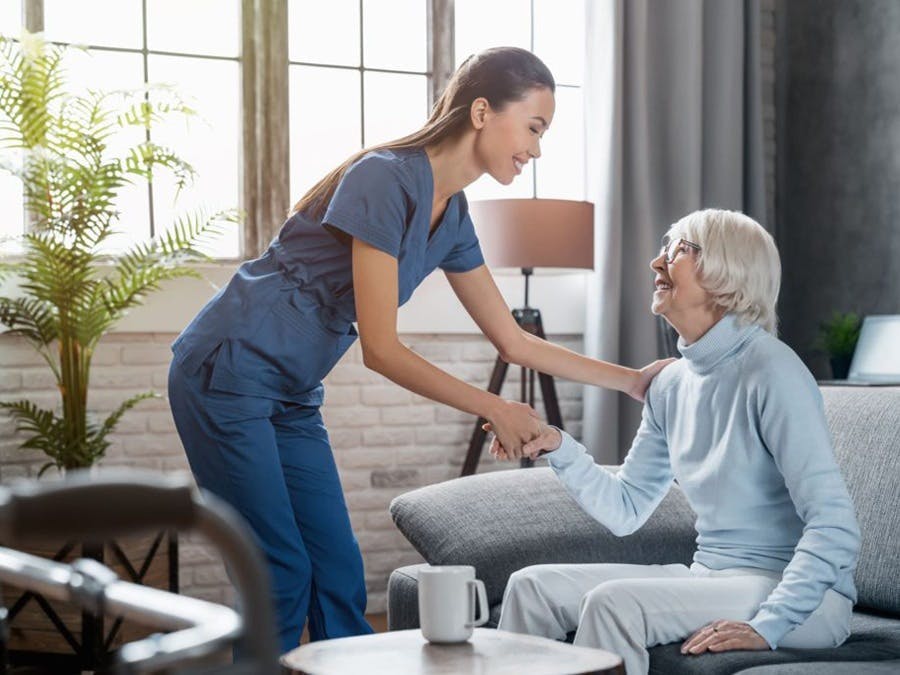 Young aid talking with woman sitting on sofa
