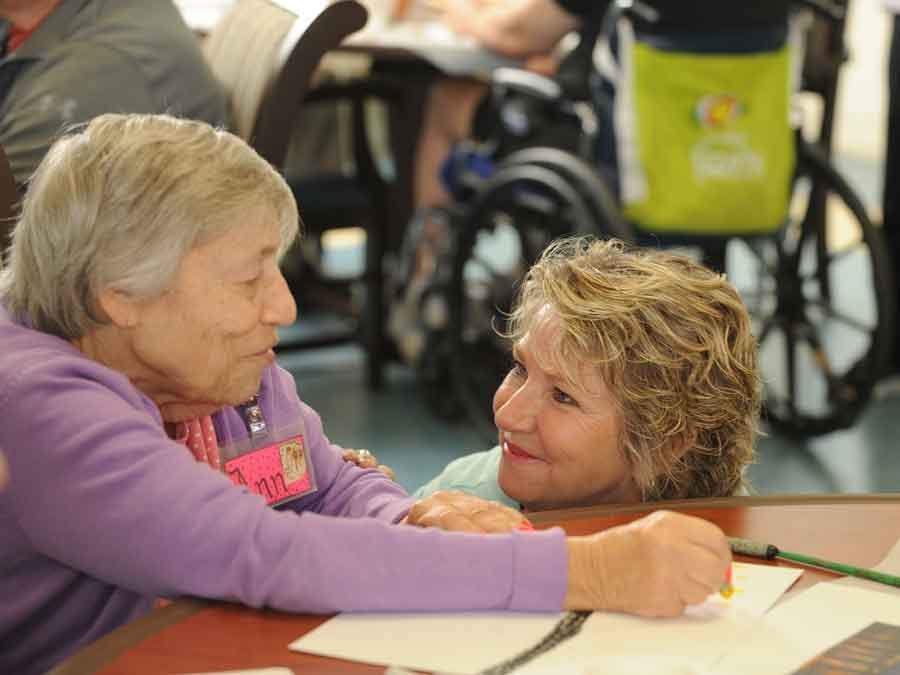 Senior woman drawing as volunteer looks on