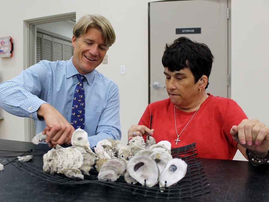 man showing woman how to make an oyster mat