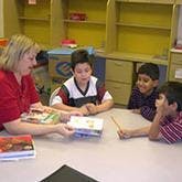 Operation Hope volunteer reading to children at table