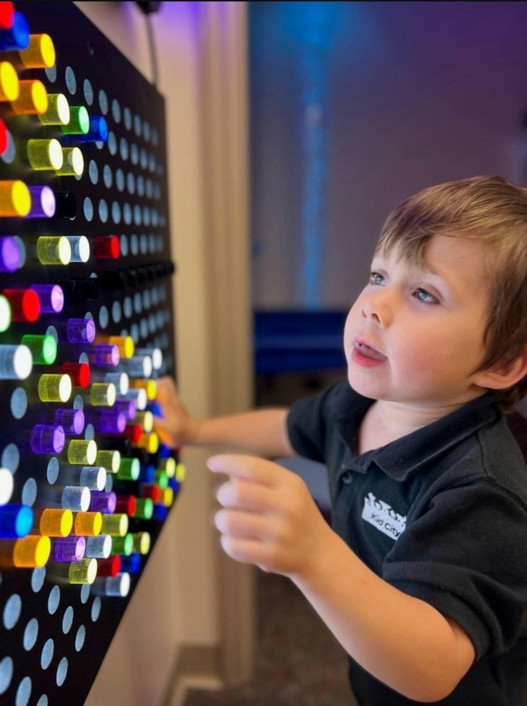Child working with colored pegs on wall