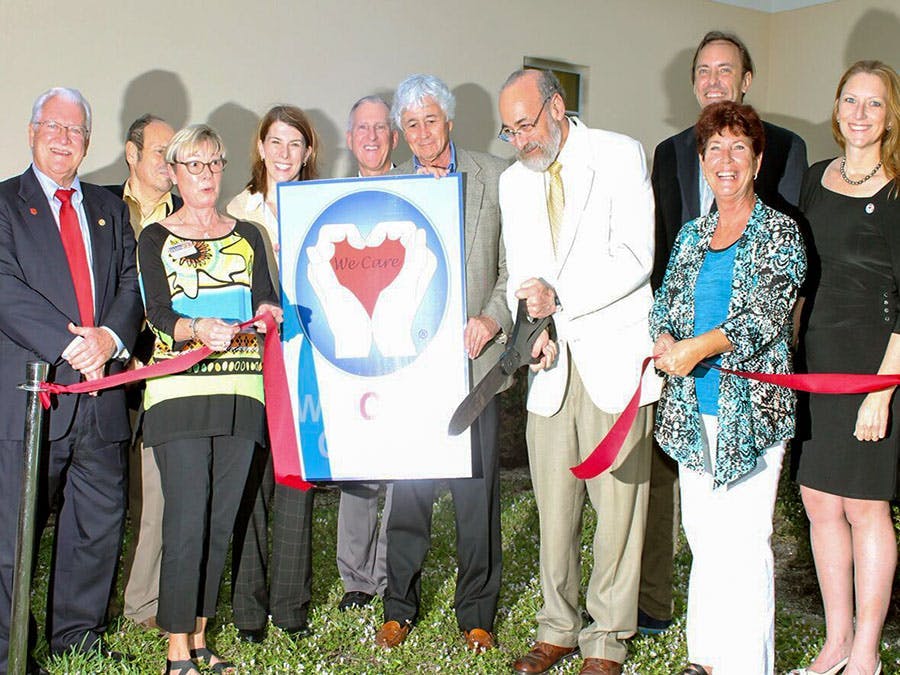 Group of doctors cutting ribbon at Grand Opening of the We Care Clinic